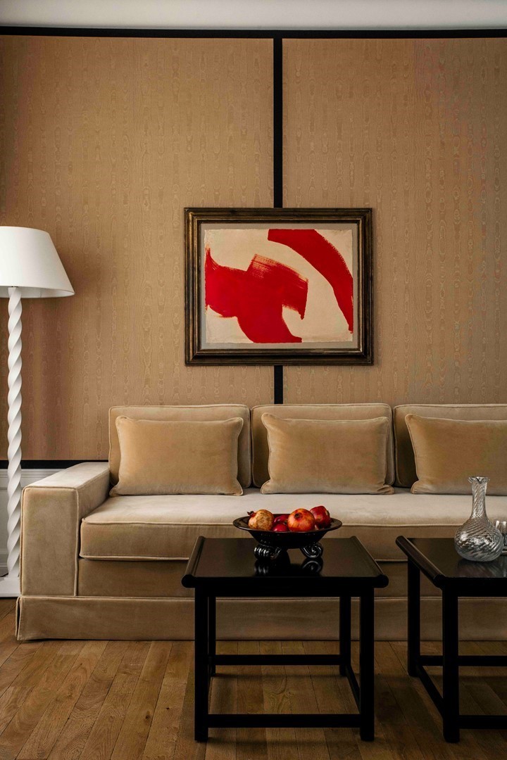 Interieur van Hotel Balzac in Parijs met beige sofa, zwarte salontafels en abstract rood schilderij aan de wand.