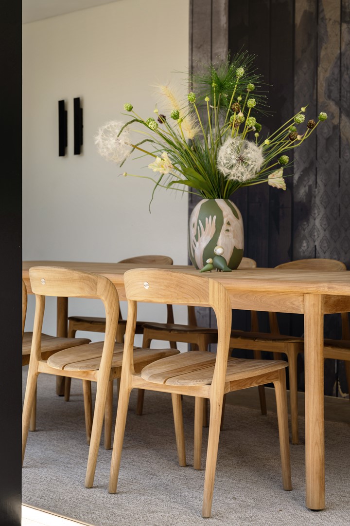 Tuinset hout met aardewerken vaas en groen boeket op tafel.