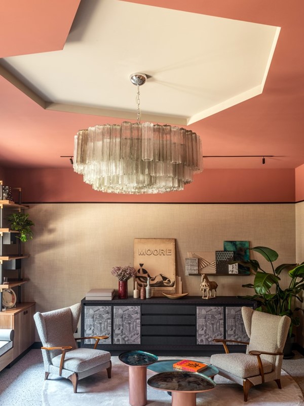 De onregelmatige uitsparing in het plafond is een idee van de bewoners. Francesca: ‘Wanneer je vanaf de straat naar boven kijkt is het effect waanzinnig mooi.’ De hanglamp is vintage en vervaardigd uit Murano-glas. De lage wandkast is een eigen ontwerp en werd bekleed met textiel van Hermès. Foto: Mark C. O’Flaherty/Living Inside.