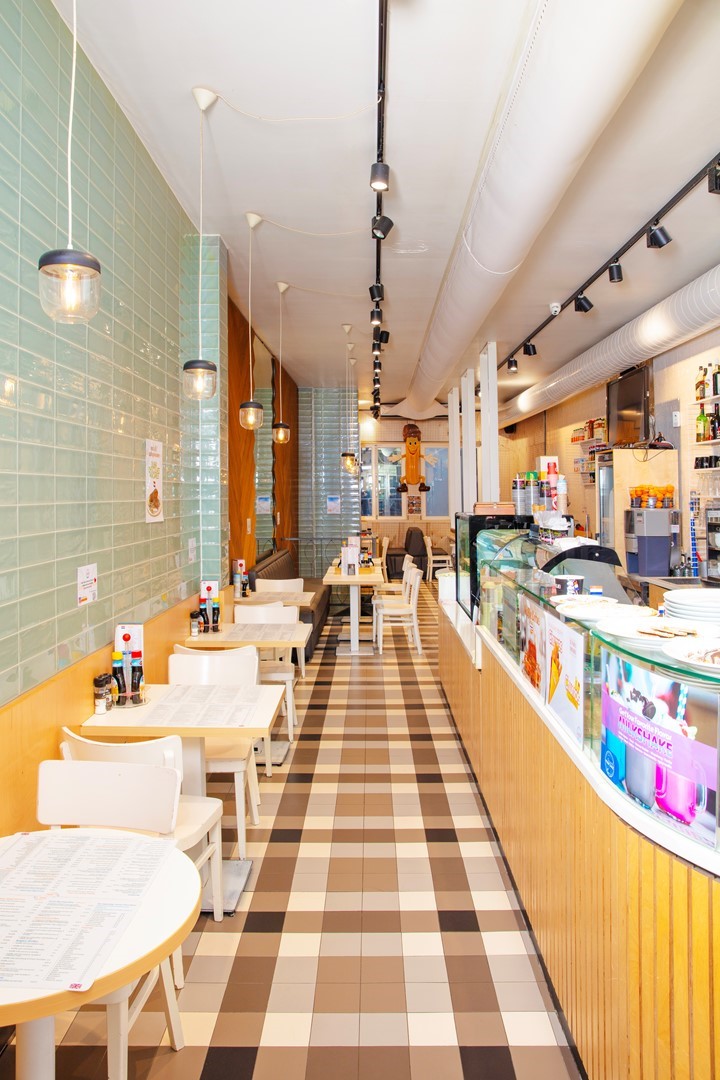 Original Pancake, diner met geruite vloer en lange toonbank met tafeltjes en stoelen voor 2 personen tegen de muur.