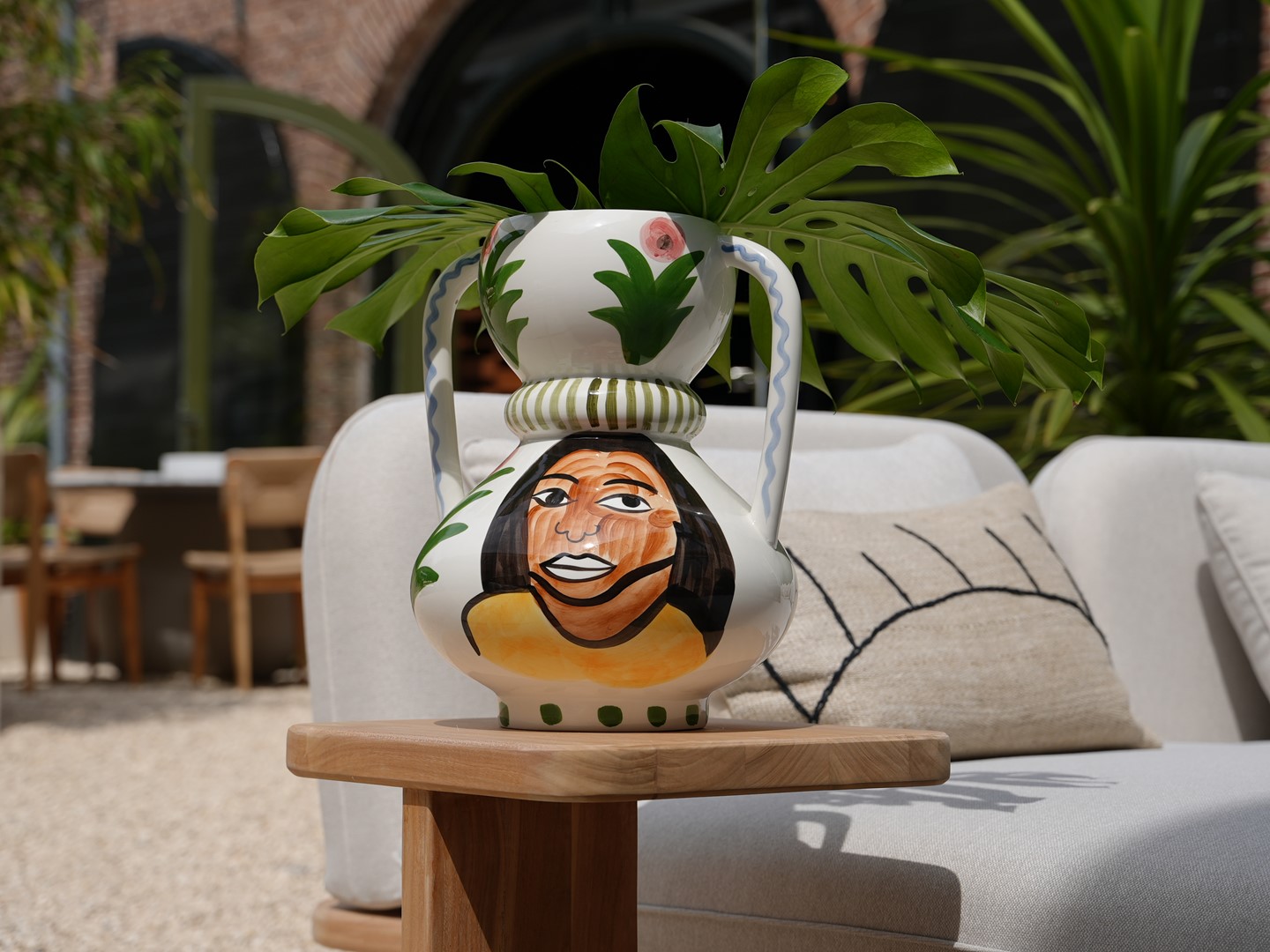 Vaas met gezicht erop geschilderd. Buiten op houten bijzettafel.