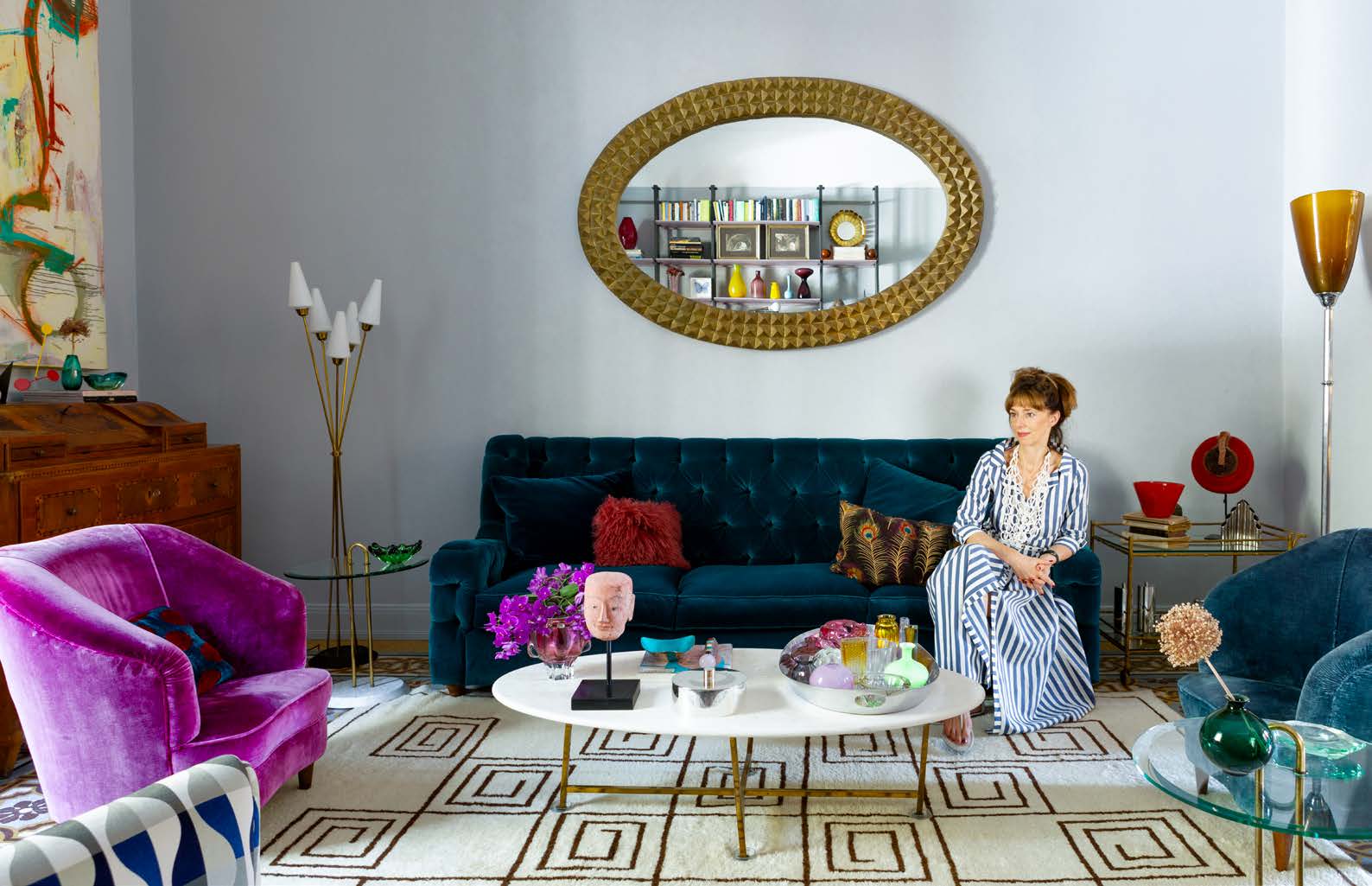 Christine Seidl op de zelf ontworpen donkerblauwe sofa die is bekleed met katoenen fluweel uit de collectie Rivoli van Manuel Canovas. Het vintage Marokkaanse tapijt is gekocht bij de Alberto Levi Galllery in Milaan. Het antieke dressoir nam Christine ooit mee uit Oostenrijk.