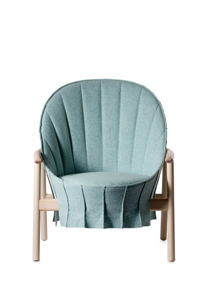 Moderne fauteuil met een ronde, schelpvormige rugleuning in lichtblauwe bekleding met verticale plooien, gecombineerd met een licht houten frame en armleuningen, afgebeeld tegen een neutrale achtergrond.