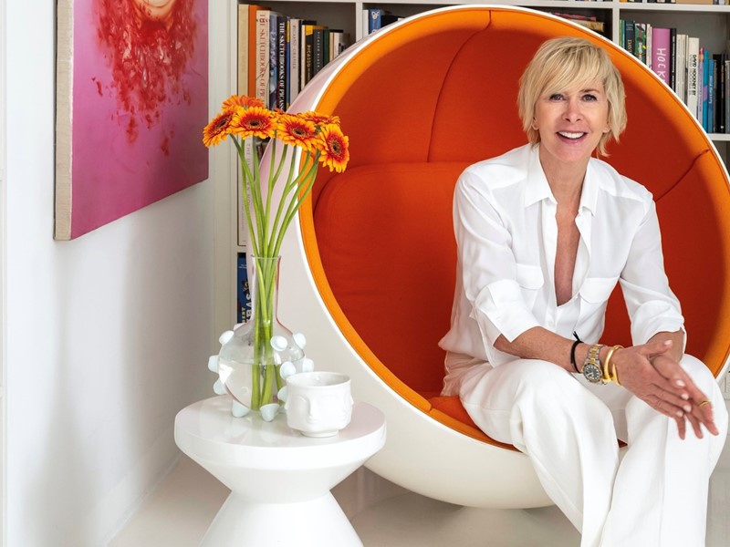 Monique des Bouvrie tussen de boeken in haar werkkamer. De stoel is een vintage Ball Chair van Eero Aarnio uit 1963. Het schilderij met juwelen heet Beyond satisfaction en is van Chen Fei.