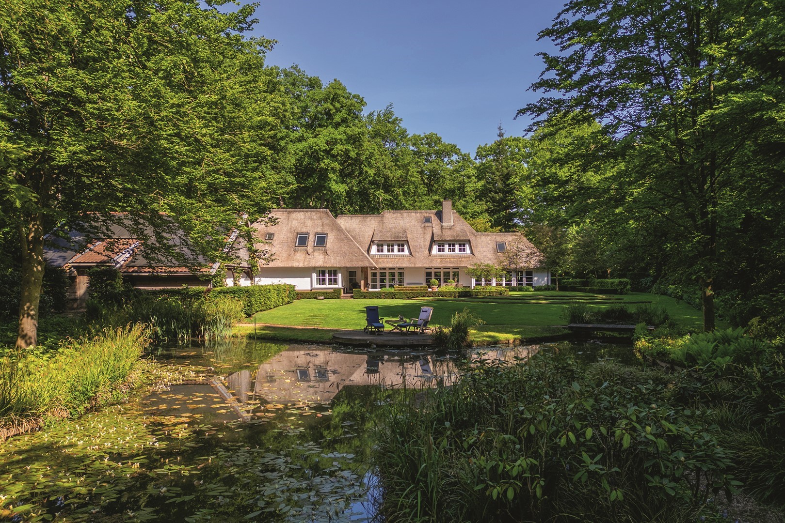Middenweg 18 in Epse, rietgedekte witte villa met uitzicht op bostuin en vijver. 