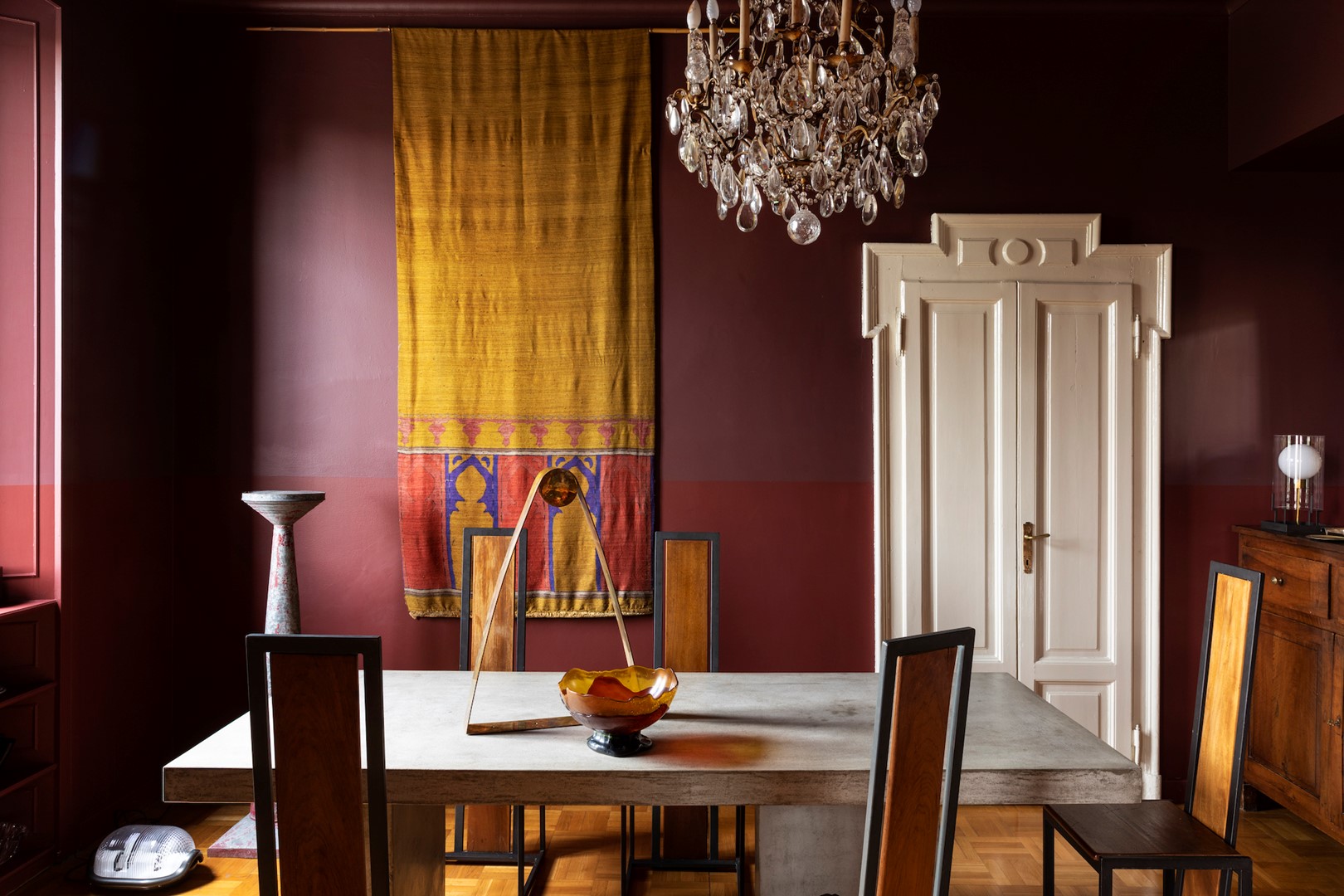 De betonnen eettafel is gemaakt door Luini12, de stoelen zijn van Gualtiero Gambigliani Zoccoli. Op de vloer links staat de Noce-lamp van Achille Castiglioni voor Flos.