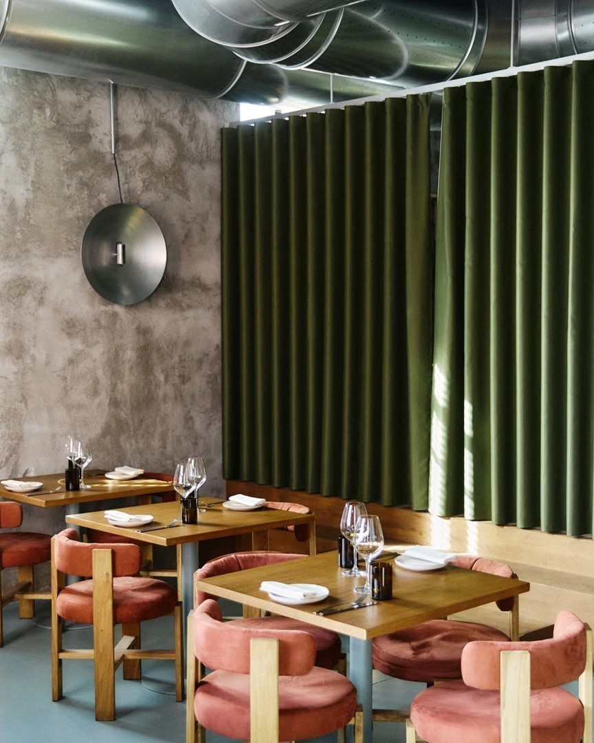 Interieur van MOGO restaurant in Isola Milaan met roze stoelen en groene gordijnen