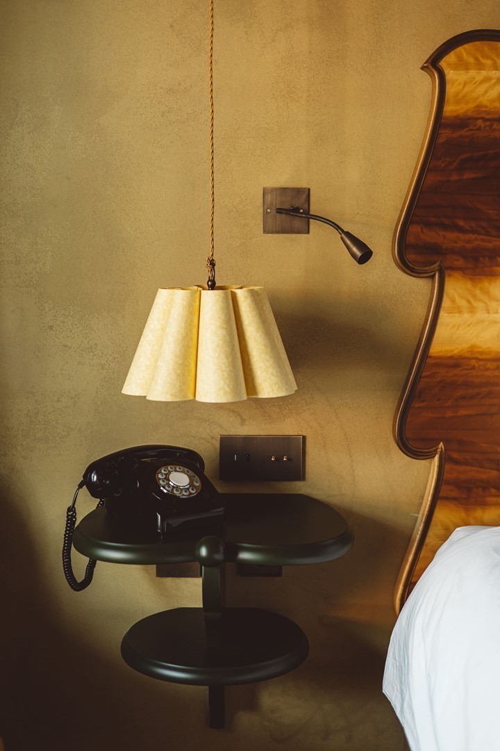 Vintage telefoon en gouden hanglamp op nachtkastje in een kamer van hotel Durgerdam