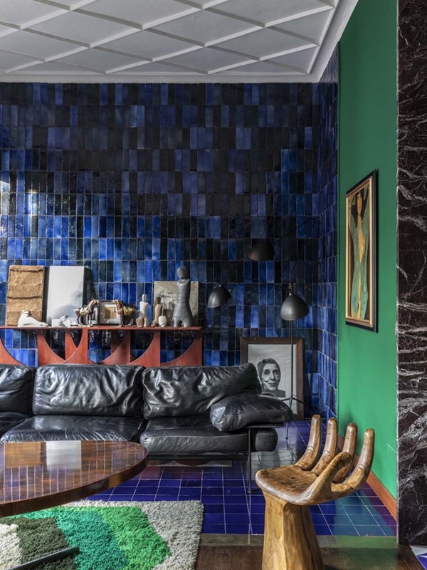 De woonkamer met originele vloerplavuizen van Bobo Piccoli. Architect Hannes Peer bekleedde de muren met donkerblauw ge mailleerde tegels van Fornace Bernasconi uit Umbri  en maakte ook zelf de donkerrode console. De ‘handstoel’ komt uit Indonesi . De vintage B&B bank is een ontwerp van Antonio Citterio en Paolo Nava.