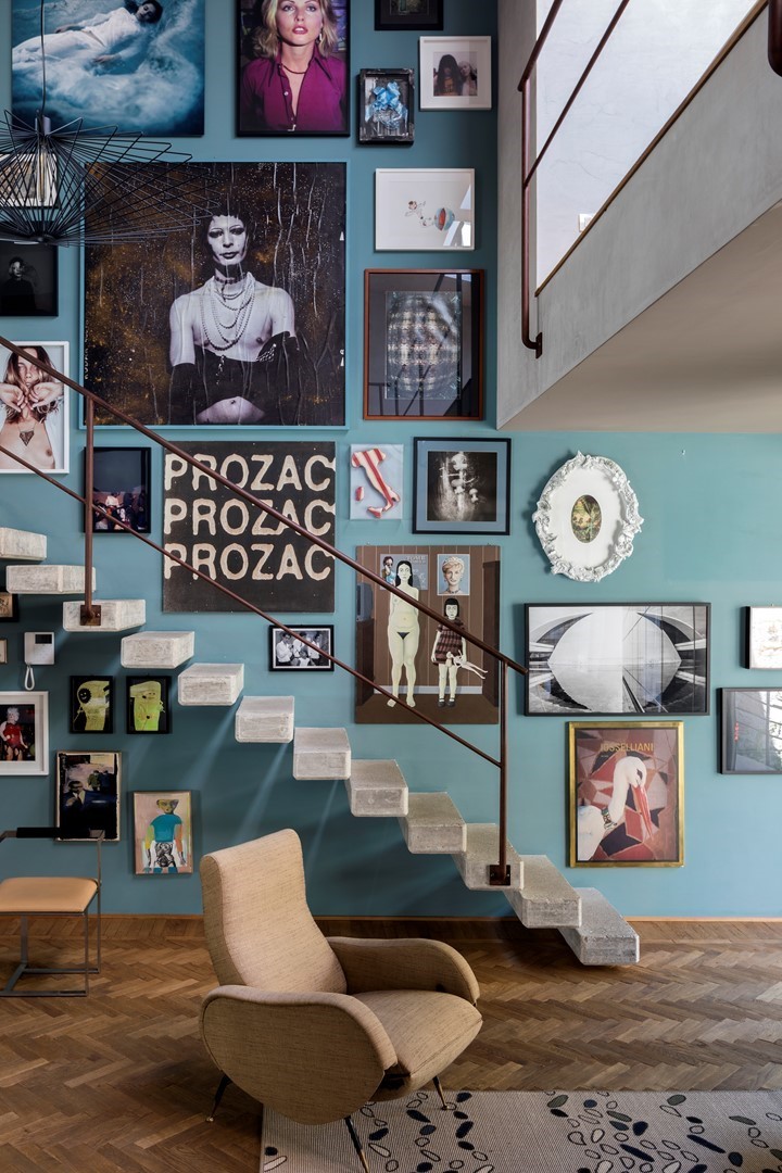 Eclectische galerie met ingelijste kunst en foto's langs betonnen trap in het interieur van Iosselliani-ontwerpers in Rome