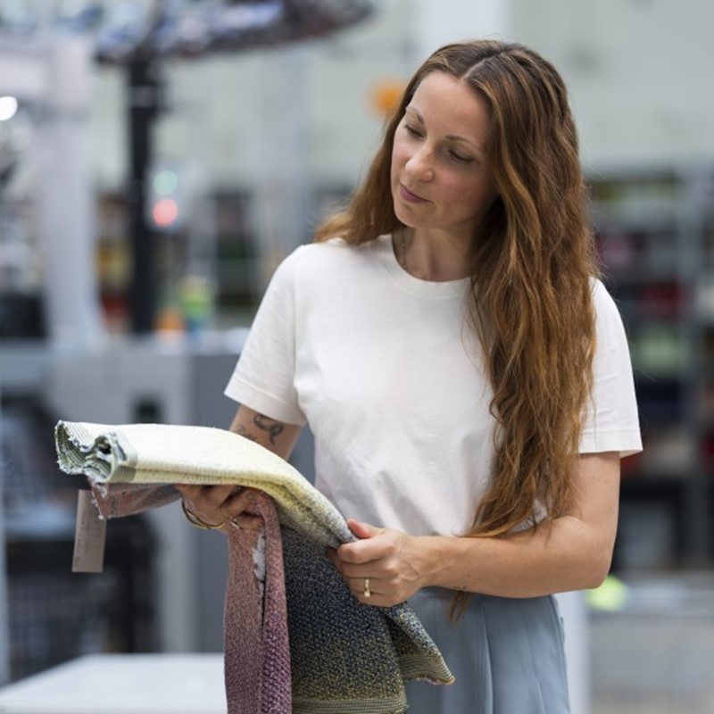 Ontwerper Mae Engelgeer in het TextielLab, bekijkt een geweven sample van Abstract Notes. Foto door Patty van den Elshout.