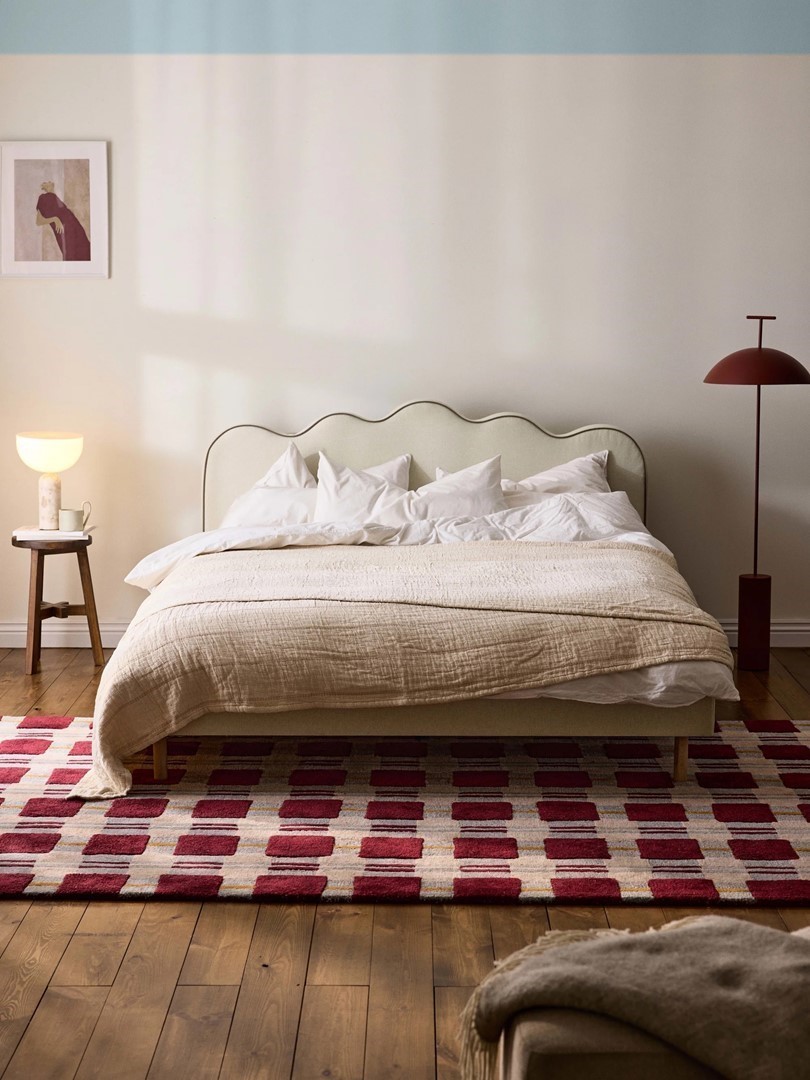 Bed met hoofdbord in zachtgroene stof met golvende rand in sfeervolle slaapkamer