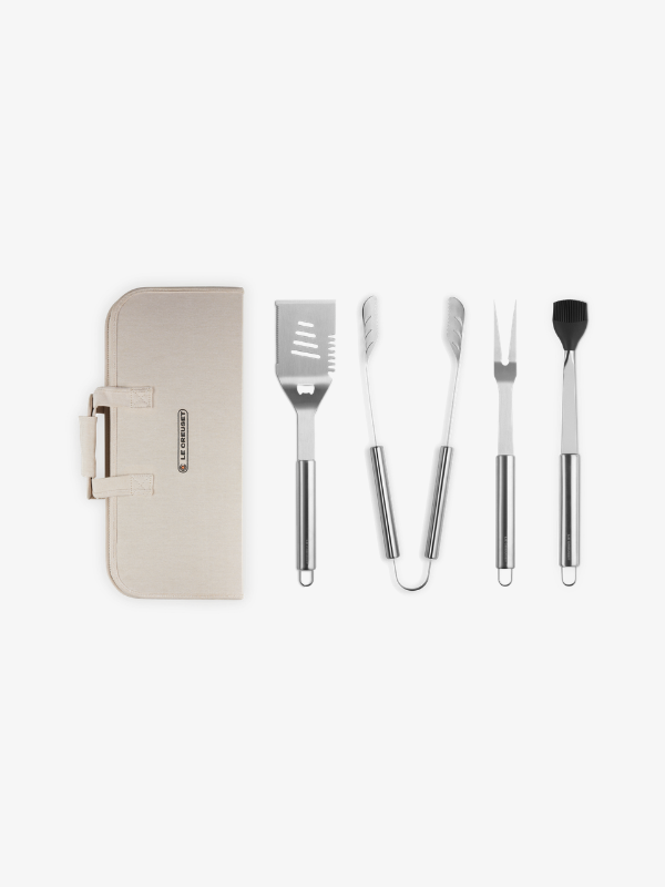 Le Creuset RVS bbq-set met spatel, tang, vork en kwast naast beige opbergtas