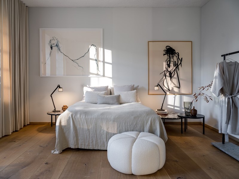 Op de voorgrond zie je een poef van VIPP. Het bed is van Auping en de gordijnen van Kvadrat.