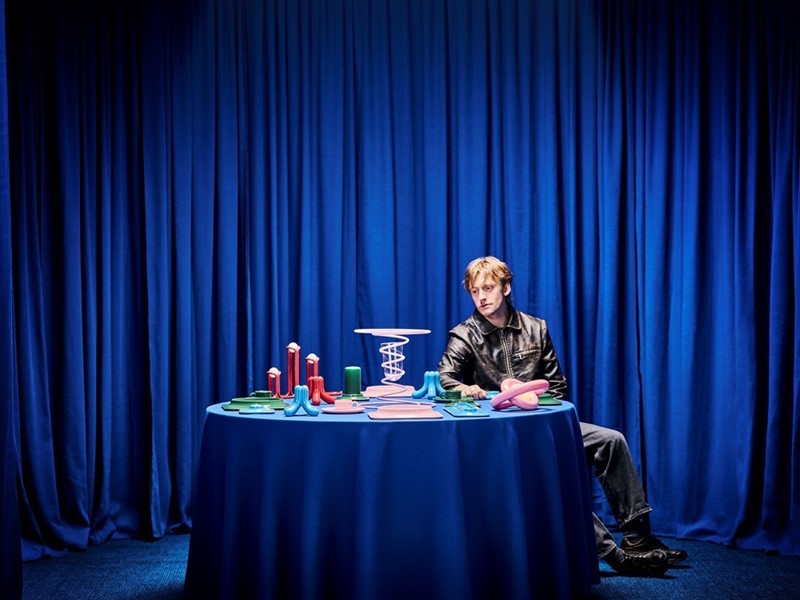 Gustaf Westman voor zijn producten ontworpen voor IKEA aan blauwe tafel.