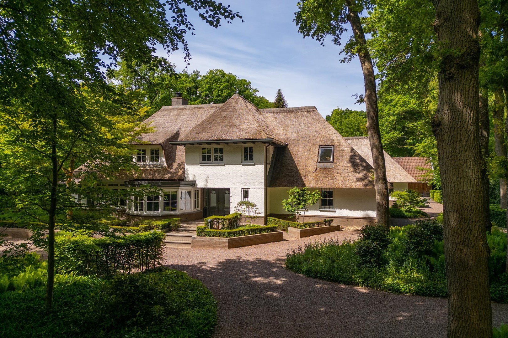 Villa 't Klein Hassink, wit woonhuis met oprijlaan omringd door de groene bostuin