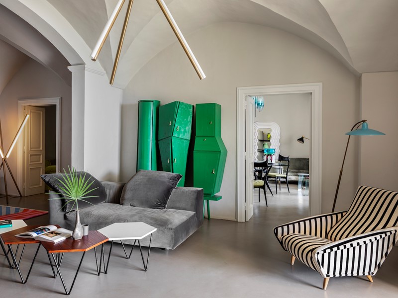 De salon met een groen wandmeubel van Pietro Consagra. De bank is de Absolu van Francesco Binfaré voor Edra. De koffietafeltjes zijn van Giò Ponti voor ISA, de vloerlamp is van Stilnovo en de hanglamp van Michael Anastassiades. De gestreepte fauteuil is een ontwerp uit 1953 van Giò Ponti.