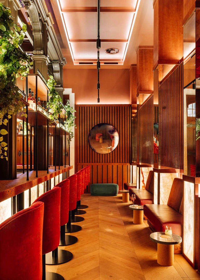 Modern designinterieur van Locke de Santa Joana in Lissabon met houten wandpanelen, rode fluwelen zitplaatsen en stijlvolle hotelbar geïnspireerd op Portugese cultuur