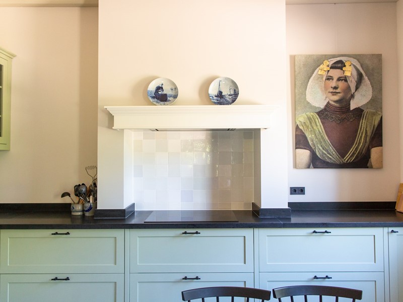 De keuken is handgemaakt en mooi ruim van opzet. De originele schouw werd in ere hersteld: modern, met een zweem nostalgie dankzij de witjes. Het Zeeuwse portret is van Hollandse Sier.