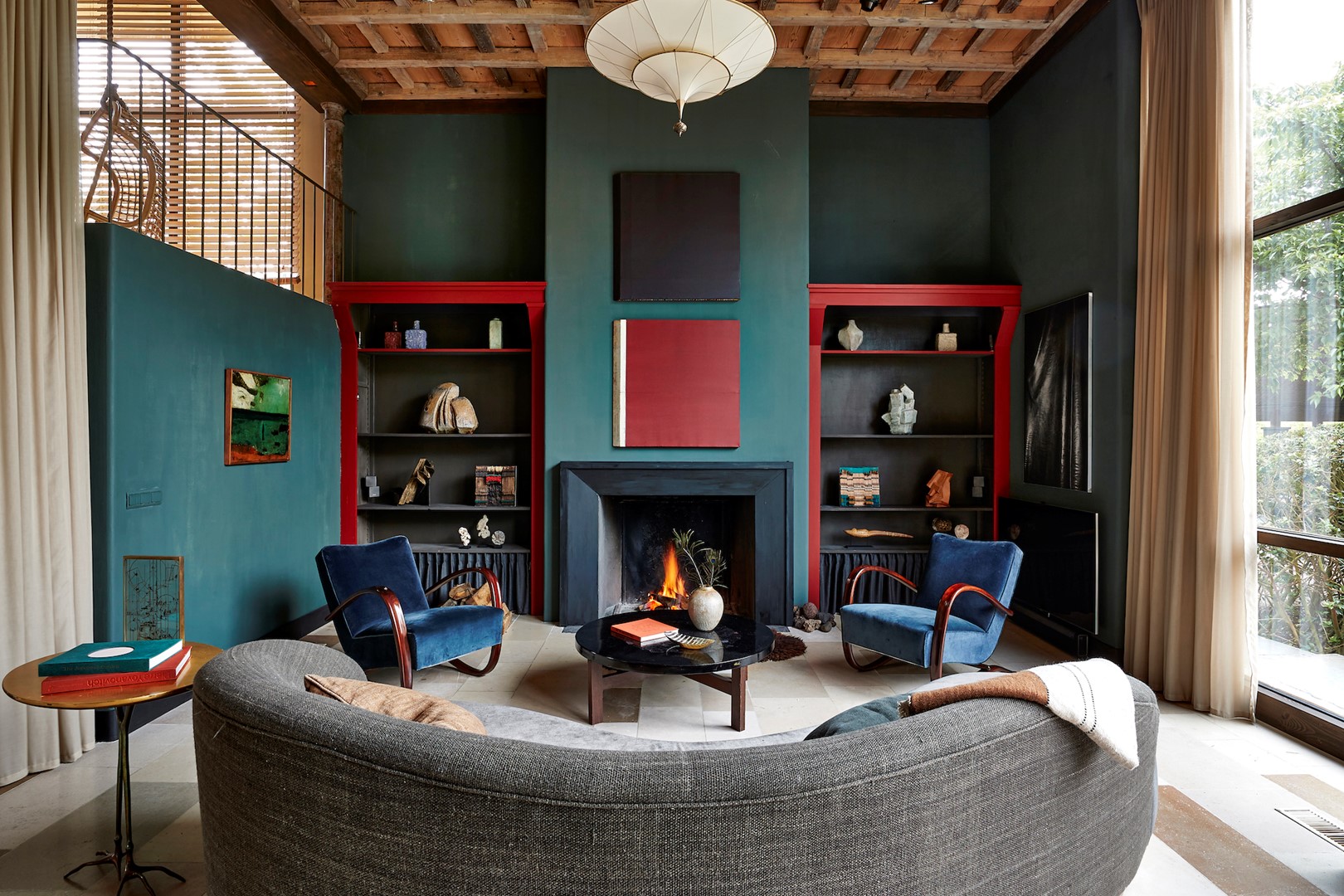 De bank is een eigen ontwerp van Joris en Caroline. De salontafel is van Ado Chale. De stoelen van Jindrich Halabala zijn opnieuw bekleed met stof van Kvadrat. Boven de haard hangen schilderijen van Michel Mouffe.