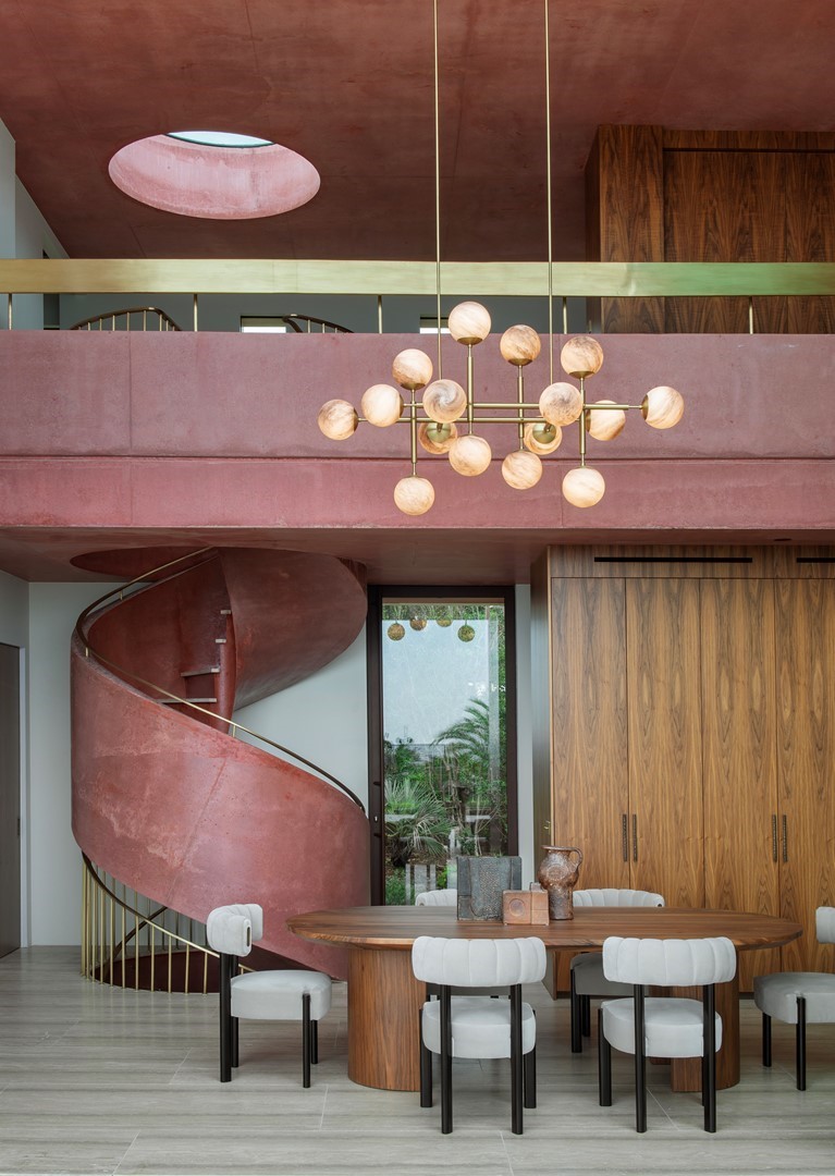 Wenteltrap van terracottakleurig beton met gouden leuning, mediterrane villa interieur