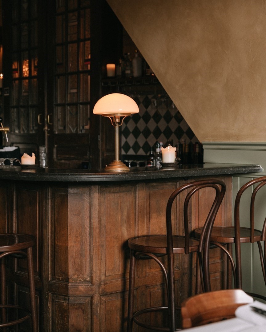 Bar van La Parole Amsterdam met houten lambrisering, ruitvormige tegels en Thonet-barkrukken