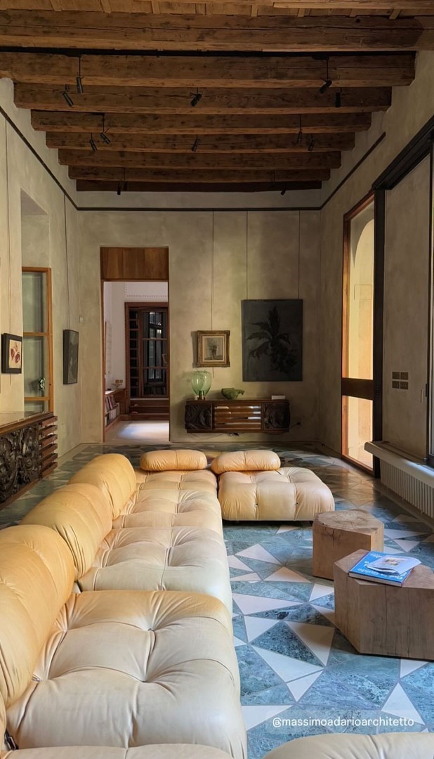 Zithoek met geel getuft bankstel op terrazzovloer in een Italiaans palazzo met houten balkenplafond