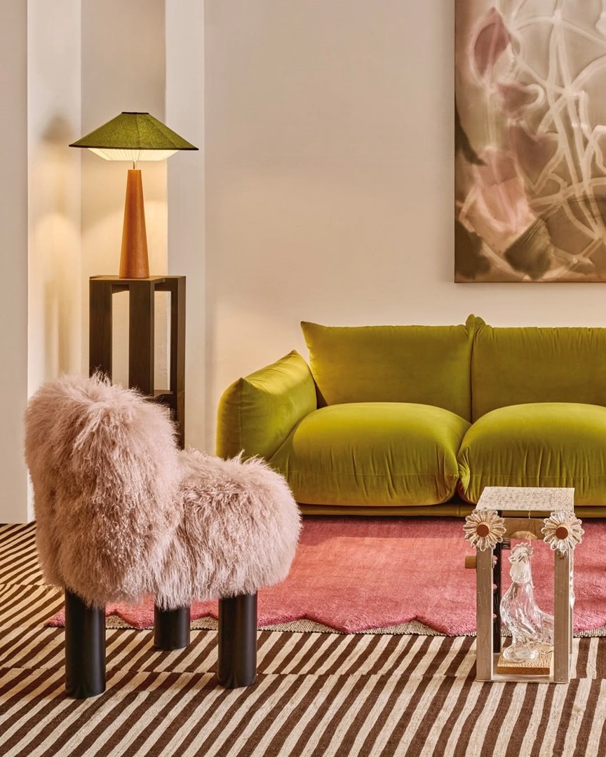 Kleurrijke meubels bij The Frozen Fountain: groene velvet bank, roze vloerkleed en sculptурale lamp in de showroom
