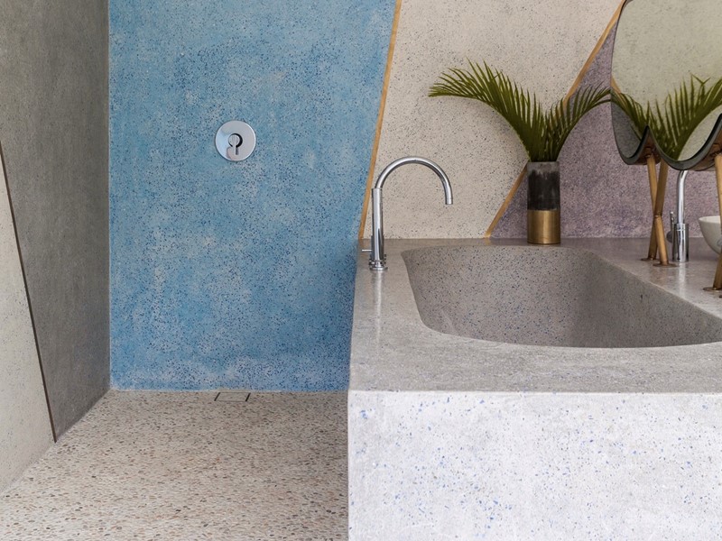 De en-suite badkamer in dit door Valentina Audrito ontworpen huis op Bali bevat veelkleurig terrazzodesign van zonnestralen met messing inleg en een ingebouwde in terrazzo ontworpen wastafel met wolkenspiegel.