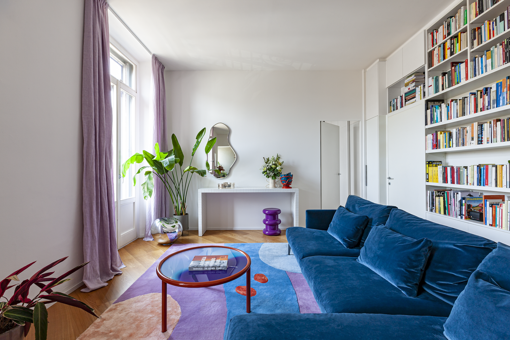 Het kleurenpallet in de woonkamer van Giulia en Beppe is geïnspireerd op het grote tapijt van Poppykalas. De tafel is de L.A Sunset uit 2020 voor Glas Italia en de blauwe bank is van Bonaldo. 