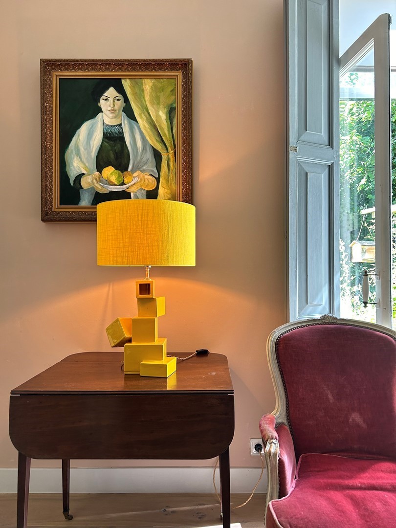 Gele keramische tafellamp van Inge Simonis in een klassiek interieur met schilderij en roze stoel