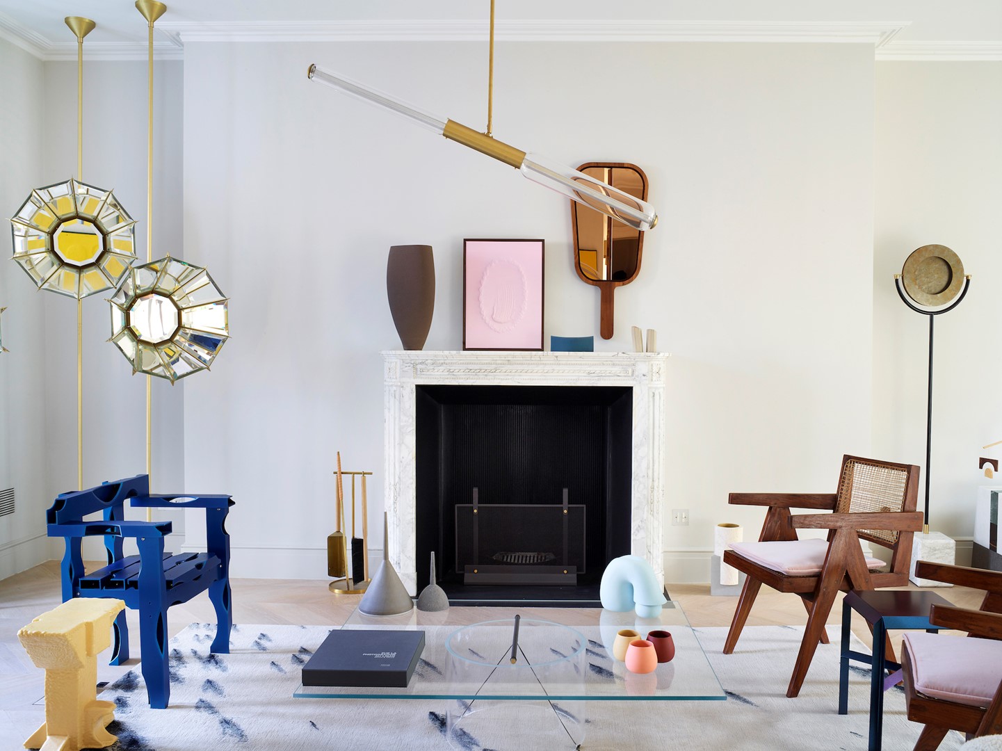 In de zitkamer achter in het huis staat een mix van vintage en modern design. De narcisvormige spiegellampen zijn van Pietro Russo, net als de hanglamp geïnspireerd door de eerste ruimtesatellieten. Nathalie Assi ontdekte Guglielmo Poletti, die de salontafel ontwierp, bij zijn afstudeerexpositie. De blauwe aluminium stoel van SOFT BAROQUE werd ontworpen voor het London Design Festival, het roze kunstwerk op de schouw is van Jesper Skov Madsen.