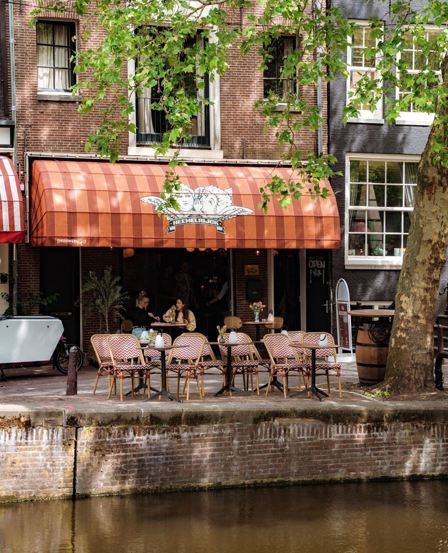 Terras van Petit Heemelrijck aan de Singel in Amsterdam, met gestreepte luifel en tafels aan het water